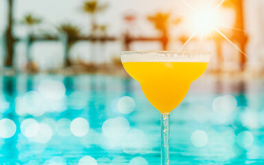 glass of pina colada next to swimming pool
