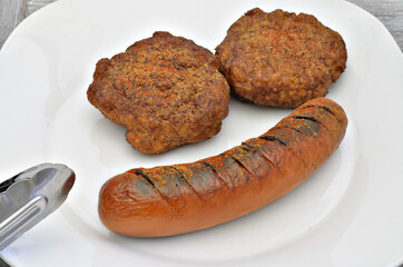 Grilled Sausages and Meatballs on Plate / grilled sausage and two meatballs on white plate, close up, macro, full frame