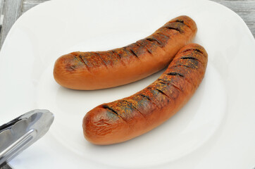 Grilled sausages on Plate / two grilled sausages on white plate, close up, full frame 