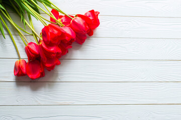 Fresh Red tulips flowers on white wooden background. Spring concept. Beautiful Card for Happy Mother’s Day, Valentine’s Day, Woman’s Day 8 March. Top view, flat lay, copy space. Floral border