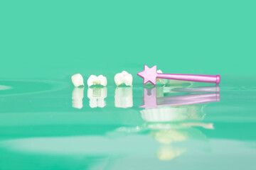 Milk teeth, tooth fairy wand and shadow of tooth fairy on green background 