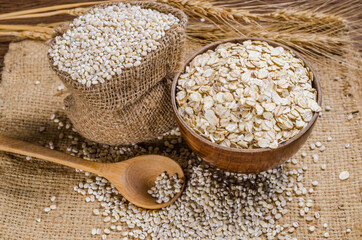 Barley flakes in wooden bowl on sackcloth