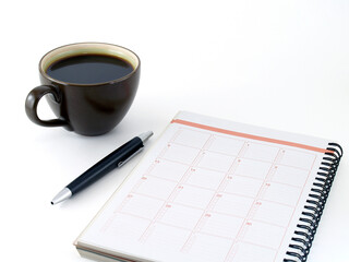 notebook, pen and dark brown ceramic cup of coffee isolated on white background, diary calendar for planning in coffee time