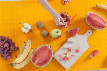 Above view of fresh fruits on yellow table eaten by little girl
