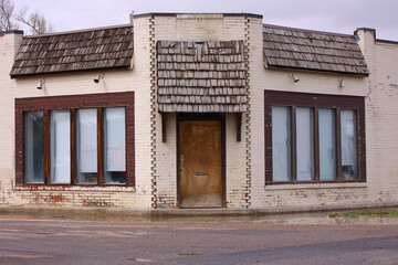 old abandoned run down dull tan building with covered windows standing on an empty corner street