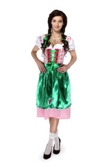 Oktoberfest! Beautiful young brunette woman with pigtails in a traditional Bavarian costume looking at camera standing on white background