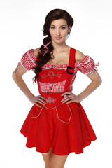 Young beautiful brunette woman dressed in red traditional Bavarian costume on white background