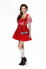 Young beautiful brunette woman dressed in red traditional Bavarian dress on white background