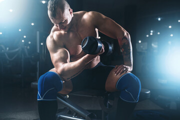 Fototapeta na wymiar Muscular male athlete lifting dumbbells