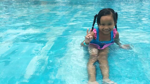 Asian little girl having fun in swimming pool, UHD 4k 3840x2160. 
