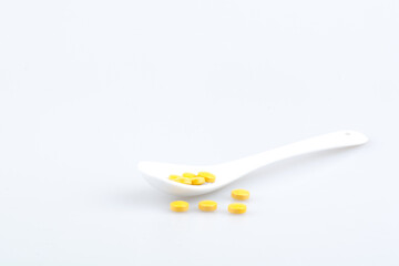 Orange pills on spoon isolated on white