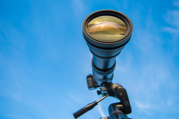 The camera with a telephoto lens on the blue sky background