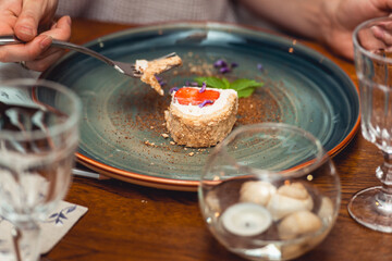 woman is eating delicious creamy dessert with strawberry on a plate in the expensive restaurant. close view
