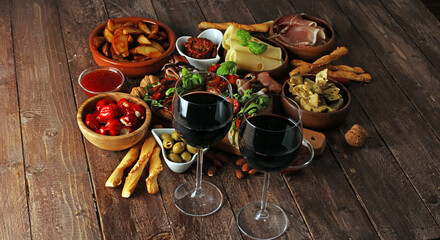 Italian antipasti wine snacks set. Cheese variety, Mediterranean olives, pickles, Prosciutto di Parma, tomatoes, artichokes and wine in glasses