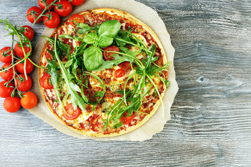 Hot true ITALIAN PIZZA with basil, arugula and cheese. TOP VIEW Tasty traditional pepperoni pizza on board on wooden table with decoration