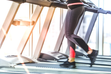 Fototapeta na wymiar The woman legs on the treadmill in the gym