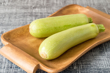  Young zucchini.  Fresh young zucchini courgettes on an old brown tray on a wooden background.