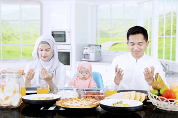 Happy family praying together in kitchen