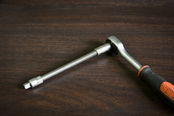 ratchet wrench with extended adapter lying on wooden table