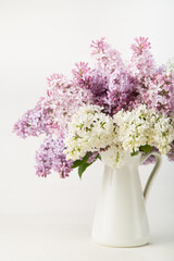 Lilac bouquet in a vase on white background