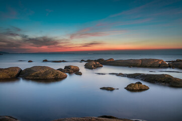 Fototapeta na wymiar Rocks on the sea with sunset green sky.