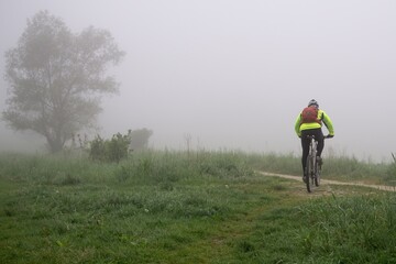 Cyclist on a meadow during foggy morning. Slovakia