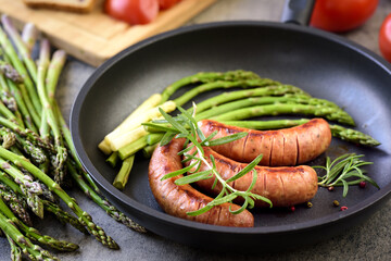 sausages with asparagus, tomatoes and rosemary on a pan
