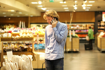Man shopping in supermarket reading product information