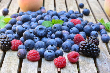 Blueberries, raspberries and peaches on a wooden table