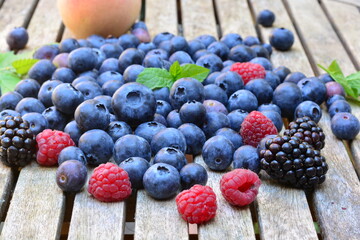 Blueberries, raspberries and peaches on a wooden table