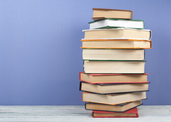Open stacking book, hardback colorful books on wooden table and blue background. Back to school. Copy space for text. Education business concept.