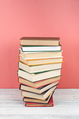 Open stacking book, hardback colorful books on wooden table, red, pink background. Back to school. Copy space for text. Education business concept.