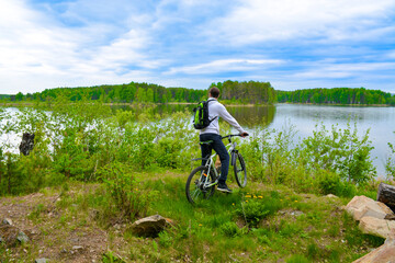 Biker with a mountain bike on the shore of a beautiful lake covered with greenery