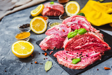 Fresh and raw meat. Still life of red meat steak ready to cook on the barbecue. Black slate background