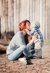 Mother kisses her child while sitting on a big tree