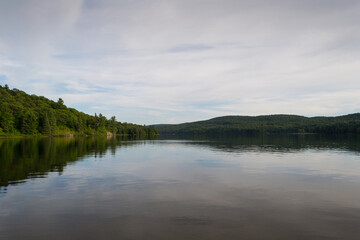 Fototapeta na wymiar Forest lake under blue cloudy sky