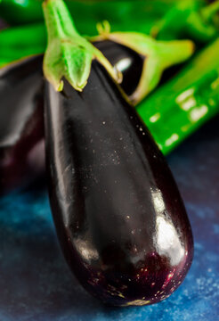 Fresh ripe purple eggplants green italian peppers on dark blue background, healthy eating concept, food ingredients, vegetarian