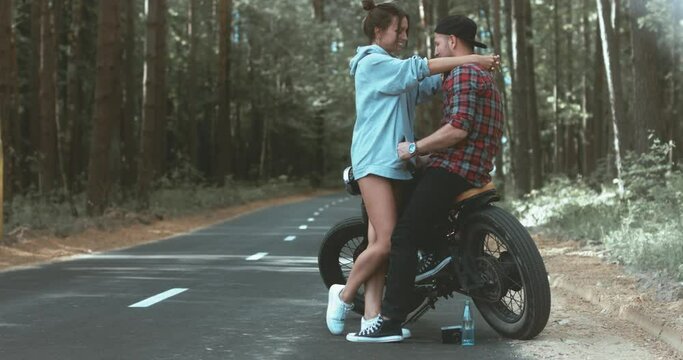 Young Caucasian couple on a motorcycle on the forest road. Love, freedom, togetherness concept. Couple travel on a motorbike. 4K UHD RAW edited footage 