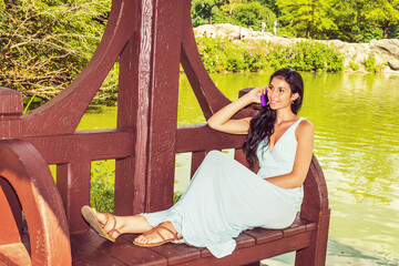 Young American Woman talking on cell phone, relaxing at Central Park, New York, in summer