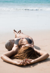 Girl in bikini daydreaming on the beach, summer vacation relaxation, vertical shot