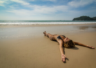 Woman in bikini soaking up the Sun on her vacation, beautiful empty beach