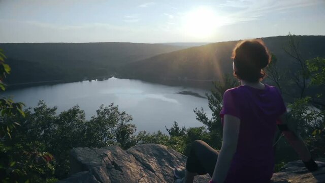 Woman seats on the mountain rocks and admiring a buatiful view