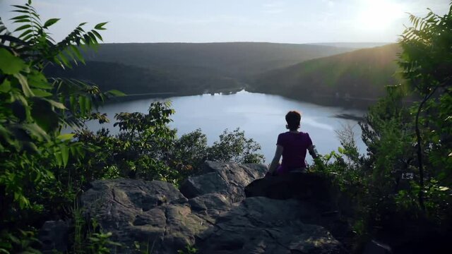 Woman seats on the mountain rocks and admiring a buatiful view