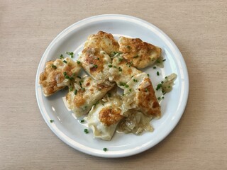 Fried pierogi on white plate and wood table from top view