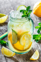 Fresh lemonade with mint, lemon and ice in glass jar on wooden background. Summer drinks and cocktails