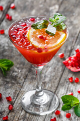 Fresh fruit red cocktail with mint, pomegranate, lemon in glass on wooden background. Summer drinks and alcoholic cocktails