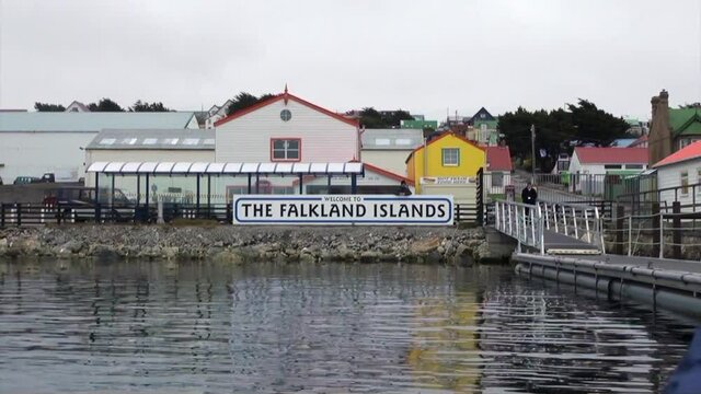 Wharf of yacht on background of clouds in sky and mountains on Falkland Islands. Beautiful landscape of wild nature. Quiet and calm ecotourism. Panorama of way to cold Antarctica.