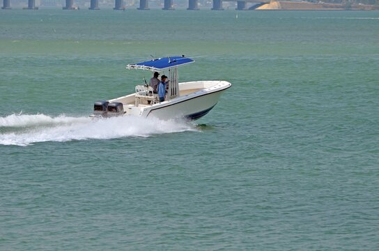 Small fishing boat p;owe red by two outboard engines speeding across the florida intra-coastal waterway off Miami Beach,