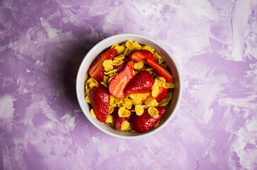 Corn flakes with fresh strawberry in bowl on the rustic background. Shallow depth of field.