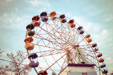 Колесо обозрения в парке развлечений с цветными кабинками на фоне неба с облаками © danysharipova